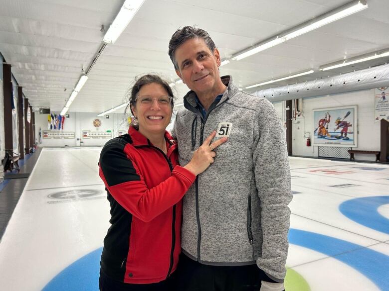 A man and a woman stand on the ice.