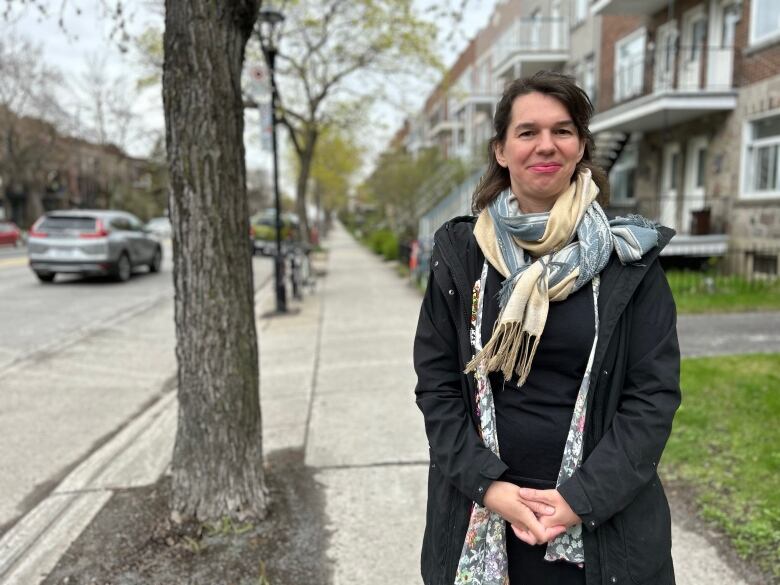 A woman standing outside and smiling at the camera. 