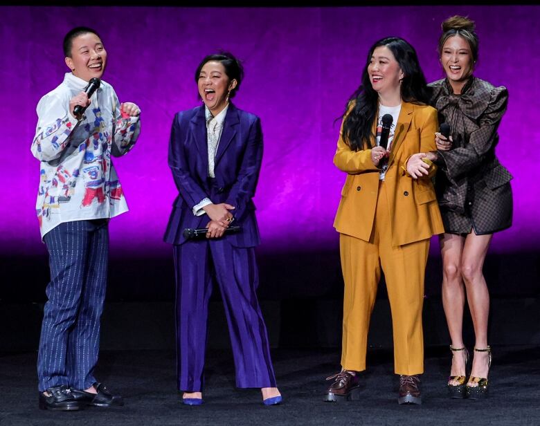 A group of women laugh on stage. 