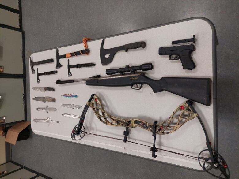 Guns, knives, and other weapons are pictured on a table.