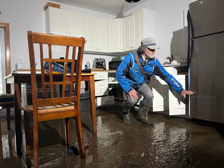 Man leans over flooded kitchen floor. 