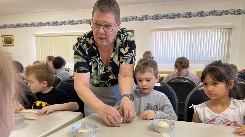 Senior and kids make bread. 