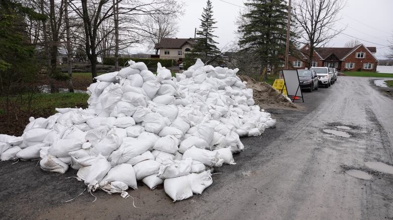 A pile of white sandbags sits on a road.