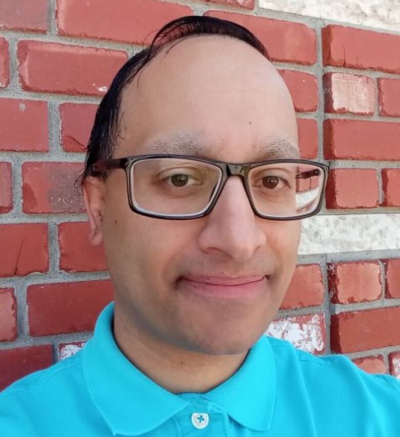 Harman Bedi is pictured next to a red brick wall. 