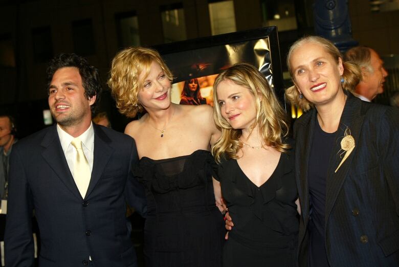 A man and three women are pictured together dressed in evening wear.