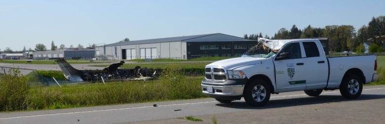 A pickup truck with its windshield broken is seen next to the wreckage of a small plane.