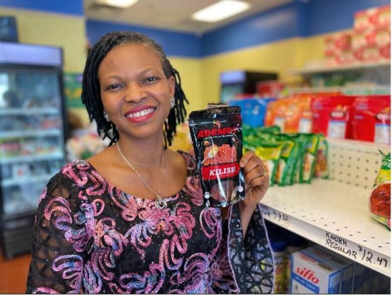 A woman inside an African store holding a pack of African beef jerky