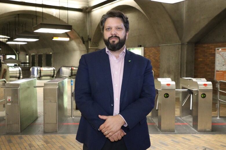 A man stands in front of metro turnstiles.