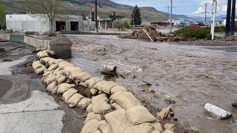 A flooded street is pictured with sandbags along one side.