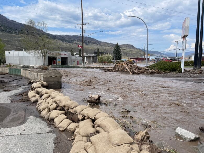 A flooded street is pictured with sandbags along one side.