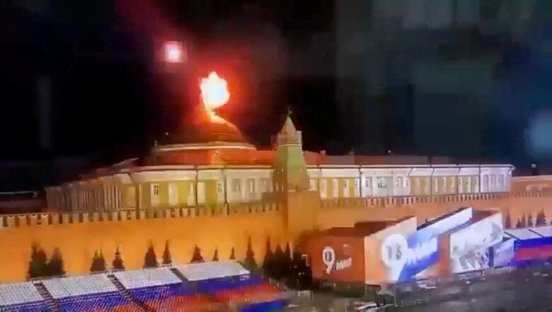 A ball of fire is seen above a wide, low-storey building with a dome.