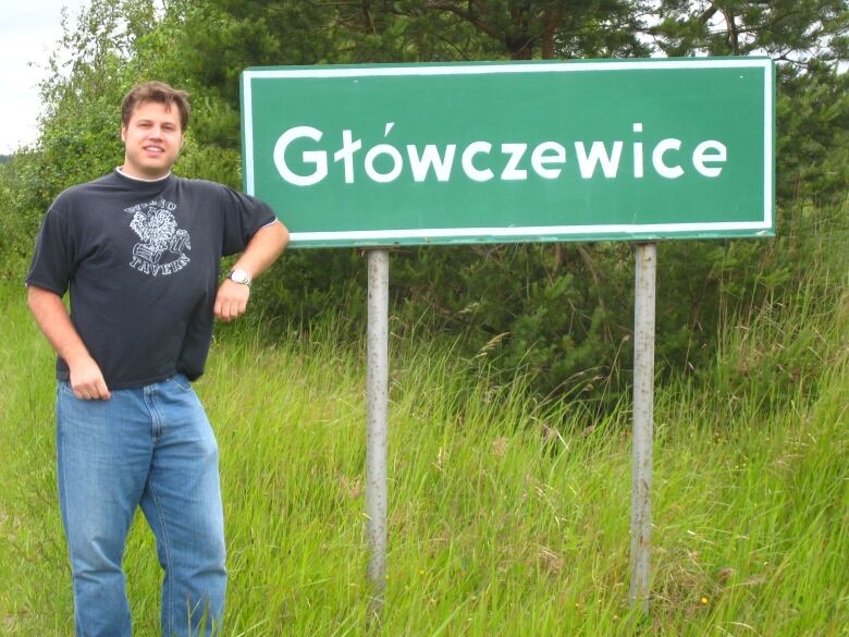 A man in front of a Polish village sign.