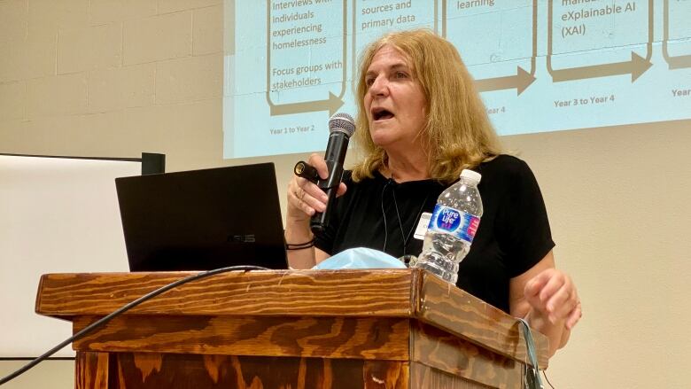 A woman speaks into a microphone at a podium.