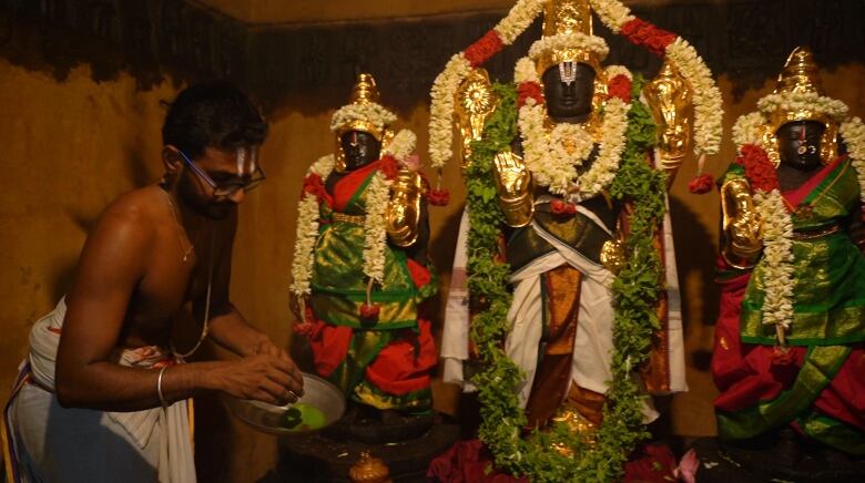 A priest at the Sundar Perumal Temple performs a ritual at an altar. 