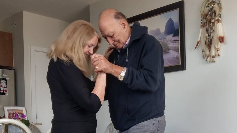 A couple dances in a home while a child plays near their feet.