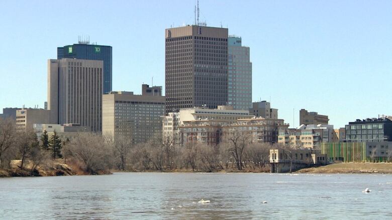 A swollen Red River with downtown Winnipeg skyscrapers in the background.