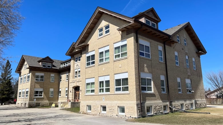 A large three-storey brick building with gabled roofs can be seen in this photo.