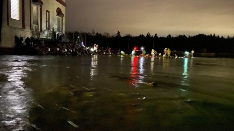 Night shot of people with lights and nets fishing in front of a dam.