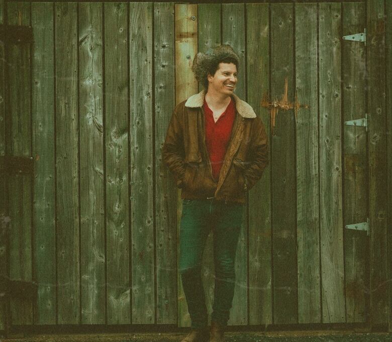 Smiling man standing infront of barn doors.