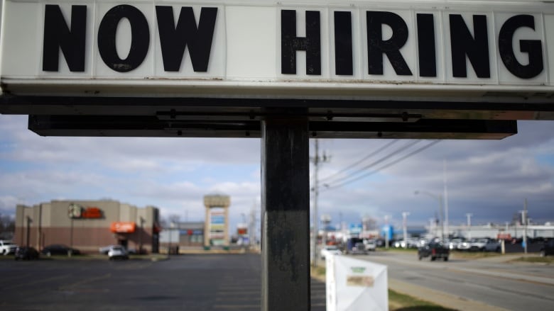 A sign announcing that the local business needs workers.