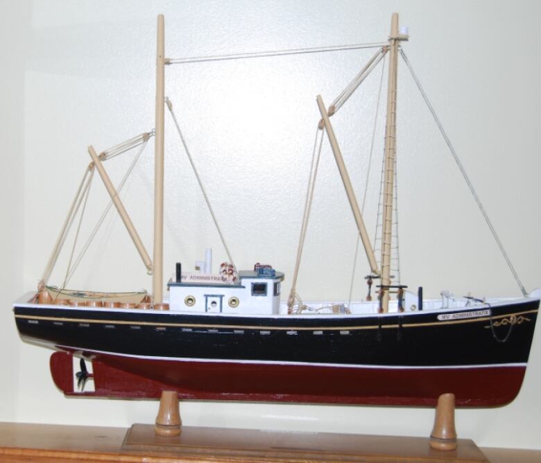 A model of a black, red and white fishing vessel sits on a table.