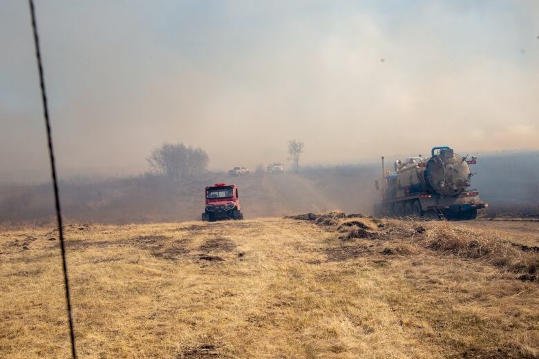 Firefighting vehichle driving across dry land covered in smoke