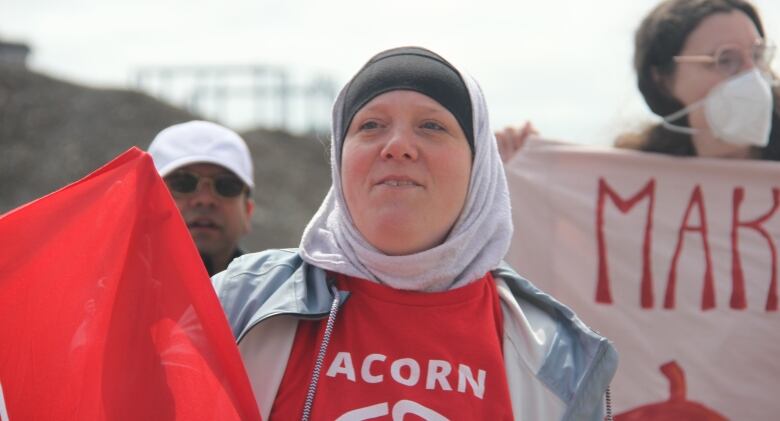 Woman in a headscarf carrying a flag and wearing an ACORN tshirt.