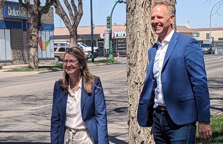 A man and a woman pose for a photo in front of blue signs. 