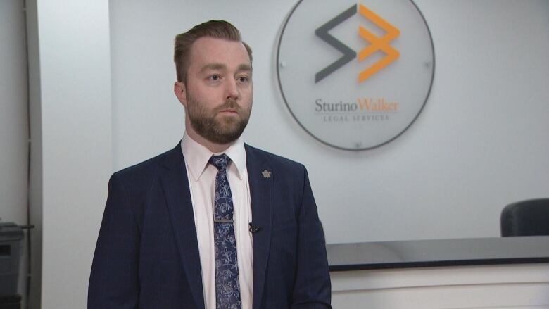 A man in a suit conducts an interview in a legal services office.