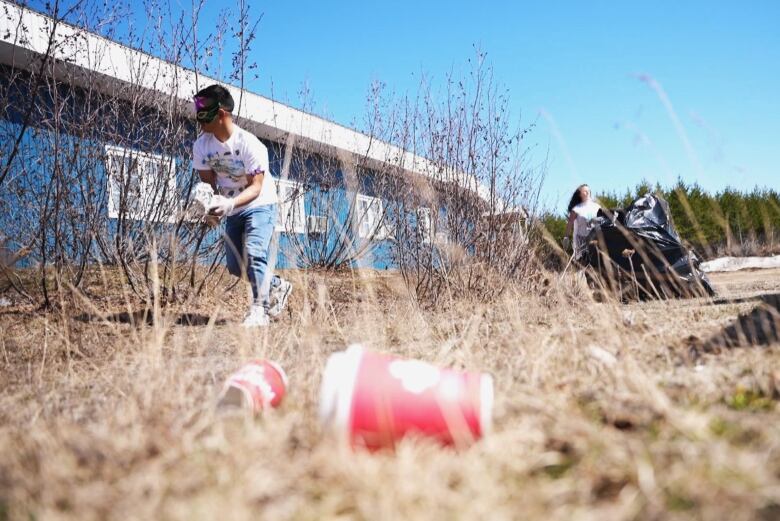 A person in a masquerade mask picks up trash. 