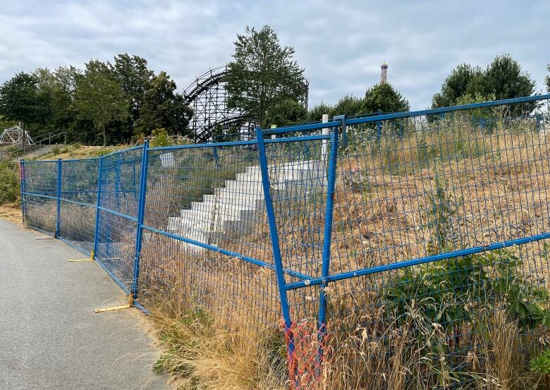 A few stairs are pictured behind blue fencing.