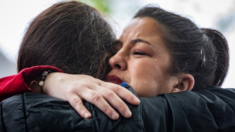 Natasha Harrison is hugged by a friend during a Red Dress Day ceremony in Vancouver on May 5, 2023. 