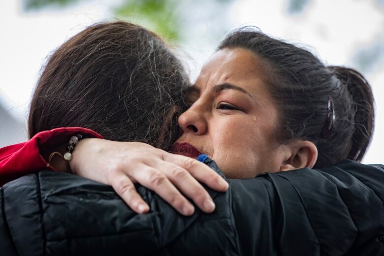 Natasha Harrison is hugged by a friend during a Red Dress Day ceremony in Vancouver on May 5, 2023. 