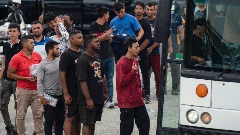 Migrants line up to board a bus in the U.S. 