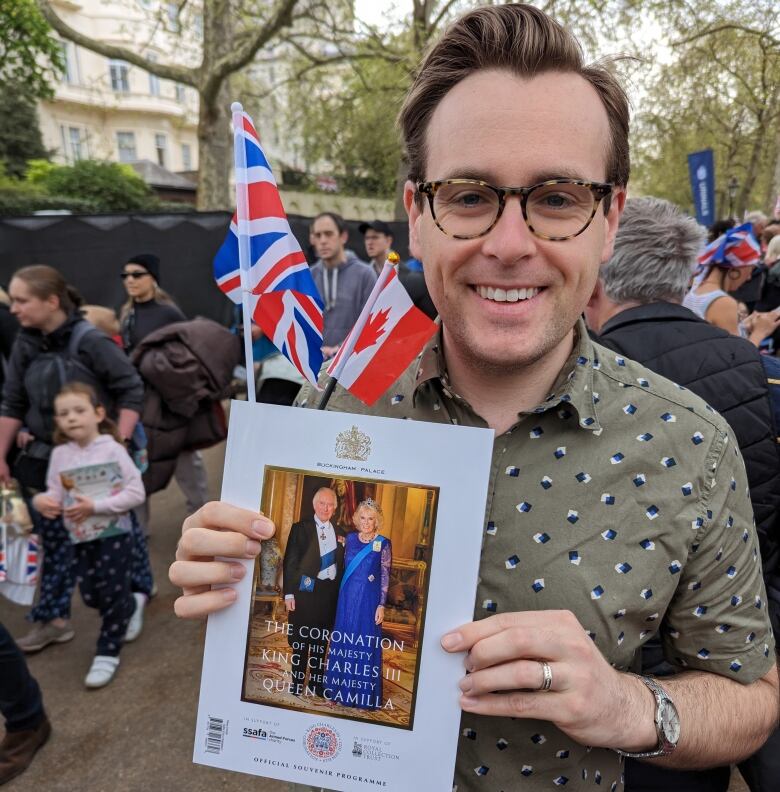 A Canadian in London for the coronation is pictured holding the official coronation programme with a Canadian flag.