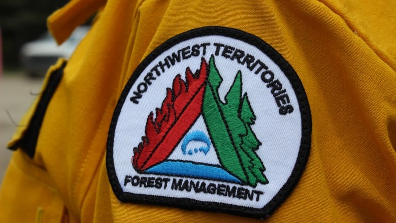 A badge that says Northwest Territories Forest Management on the shoulder of a yellow uniform.