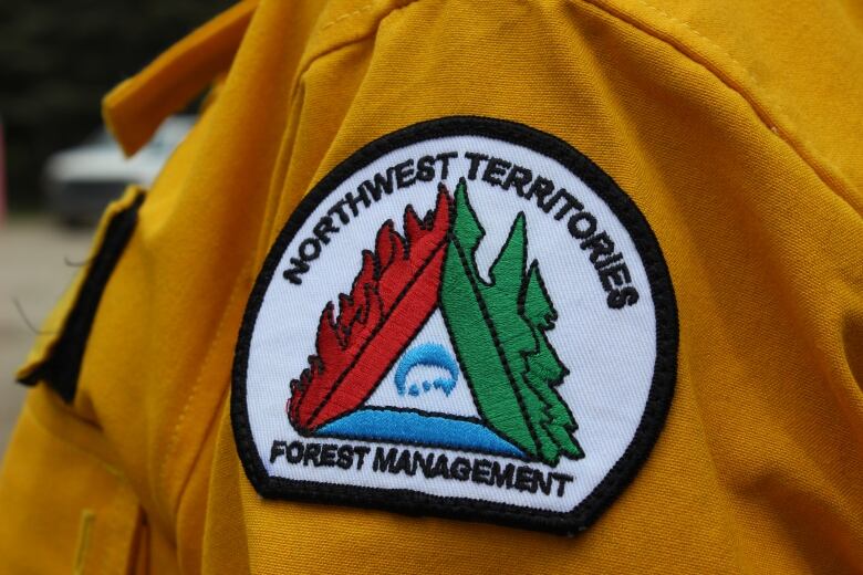 A badge that says Northwest Territories Forest Management on the shoulder of a yellow uniform.