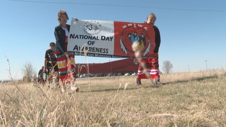 Two people walking holding a sign that read National Day of Awareness.