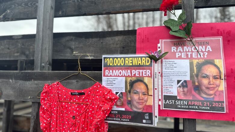 The photo shows a red dress, a red rose and two posters of a missing woman.