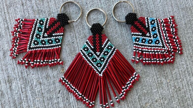 Three beaded keychains feature designs of women wearing fancy shawls.