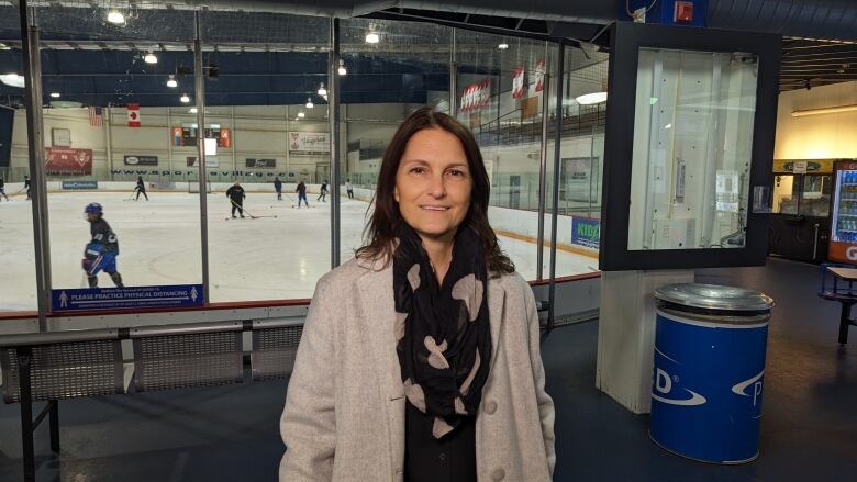 Lesley smiles standing with an indoor hockey rink in the background.