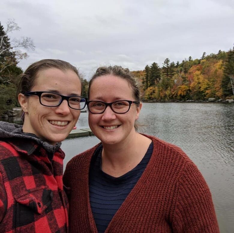 Two smiling women at a lake.