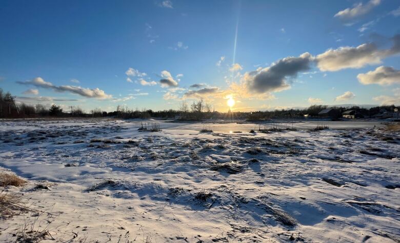 The sun sets over a frozen waterway.