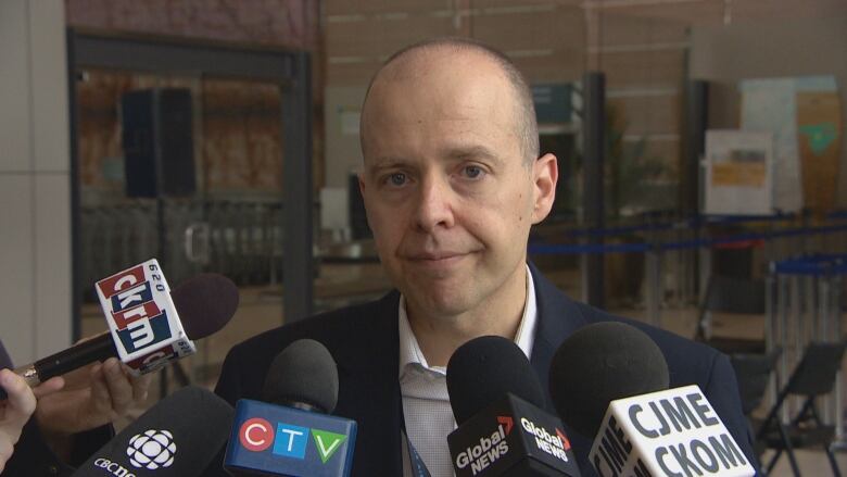 A man with multiple microphones in front of him is being interviewed. 