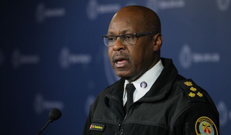 A man in formal police clothing speaks at a microphone.