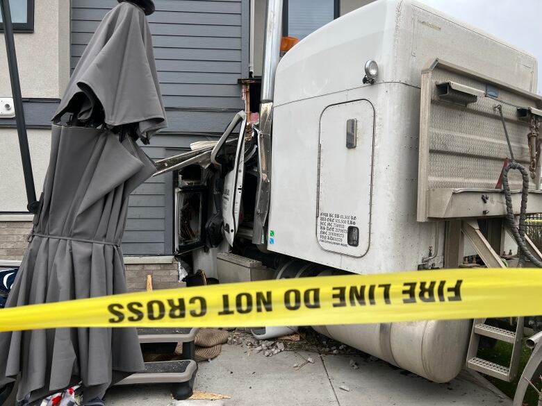 A truck embedded into a house, with yellow tapes around.