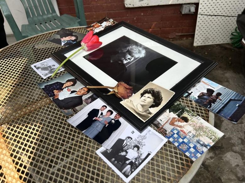 Photos and flowers are spread out on a table.