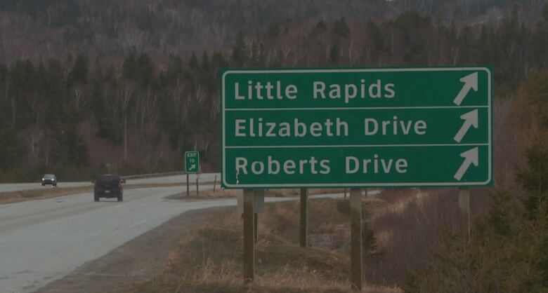 A green and white sign on the side of a highway. 