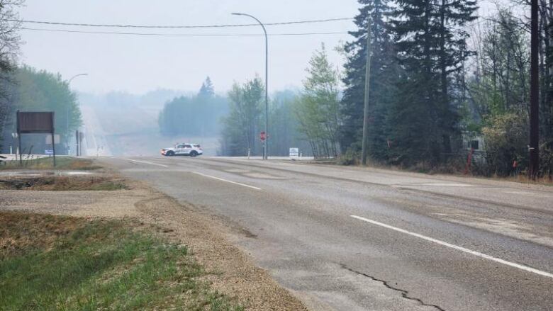 View of a long road with a police car and smoke in the distance