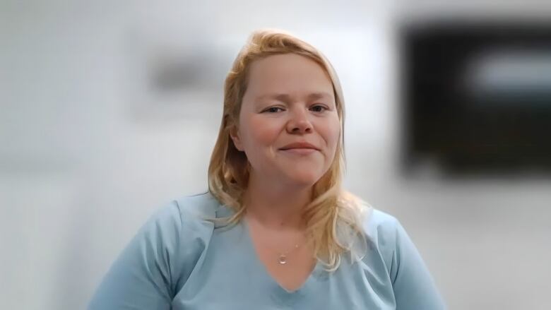 A white blonde woman is seen on a Zoom screen wearing a blue shirt